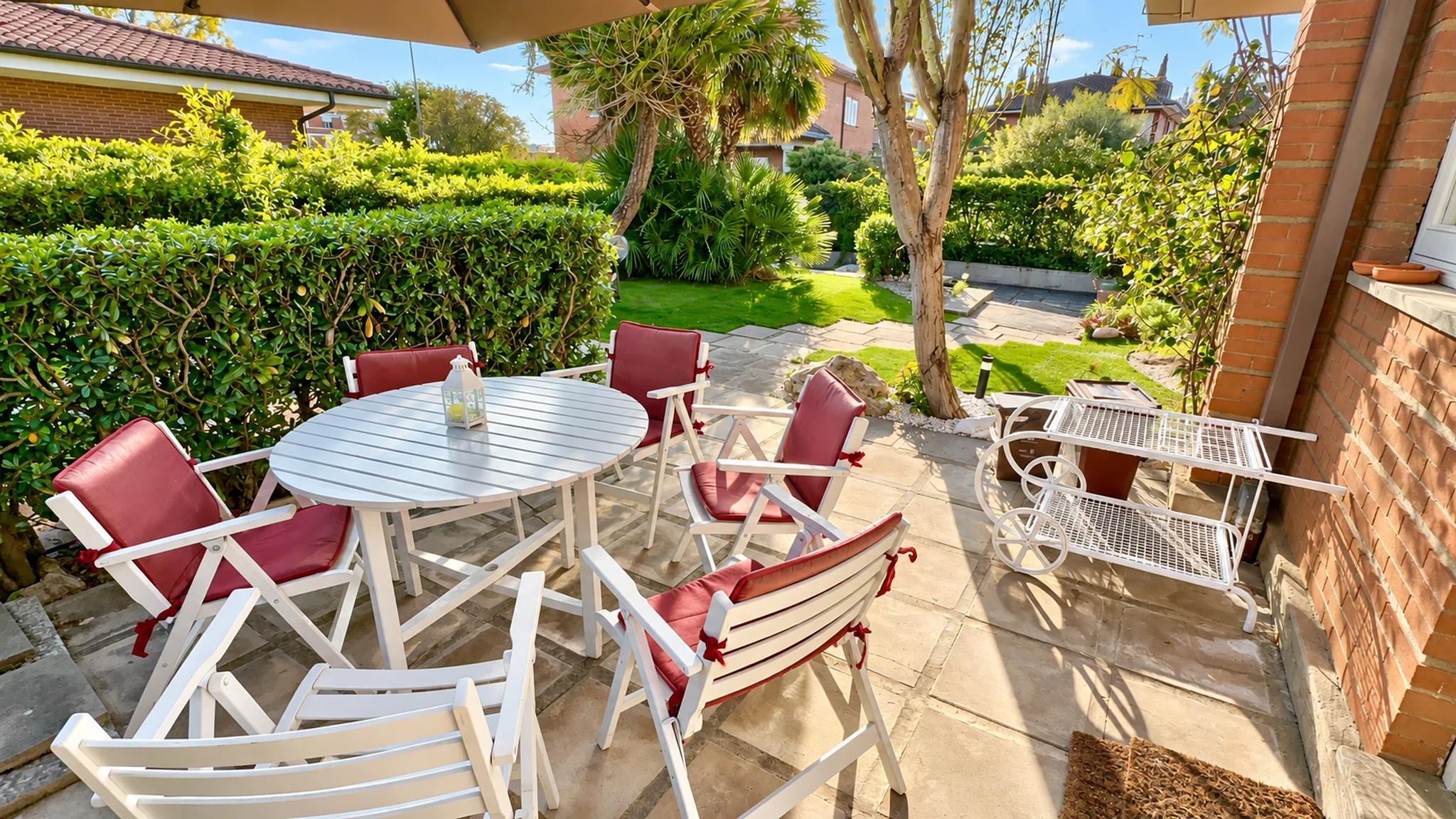 Garden table with red cushioned chairs under the umbrella at Villa Brando