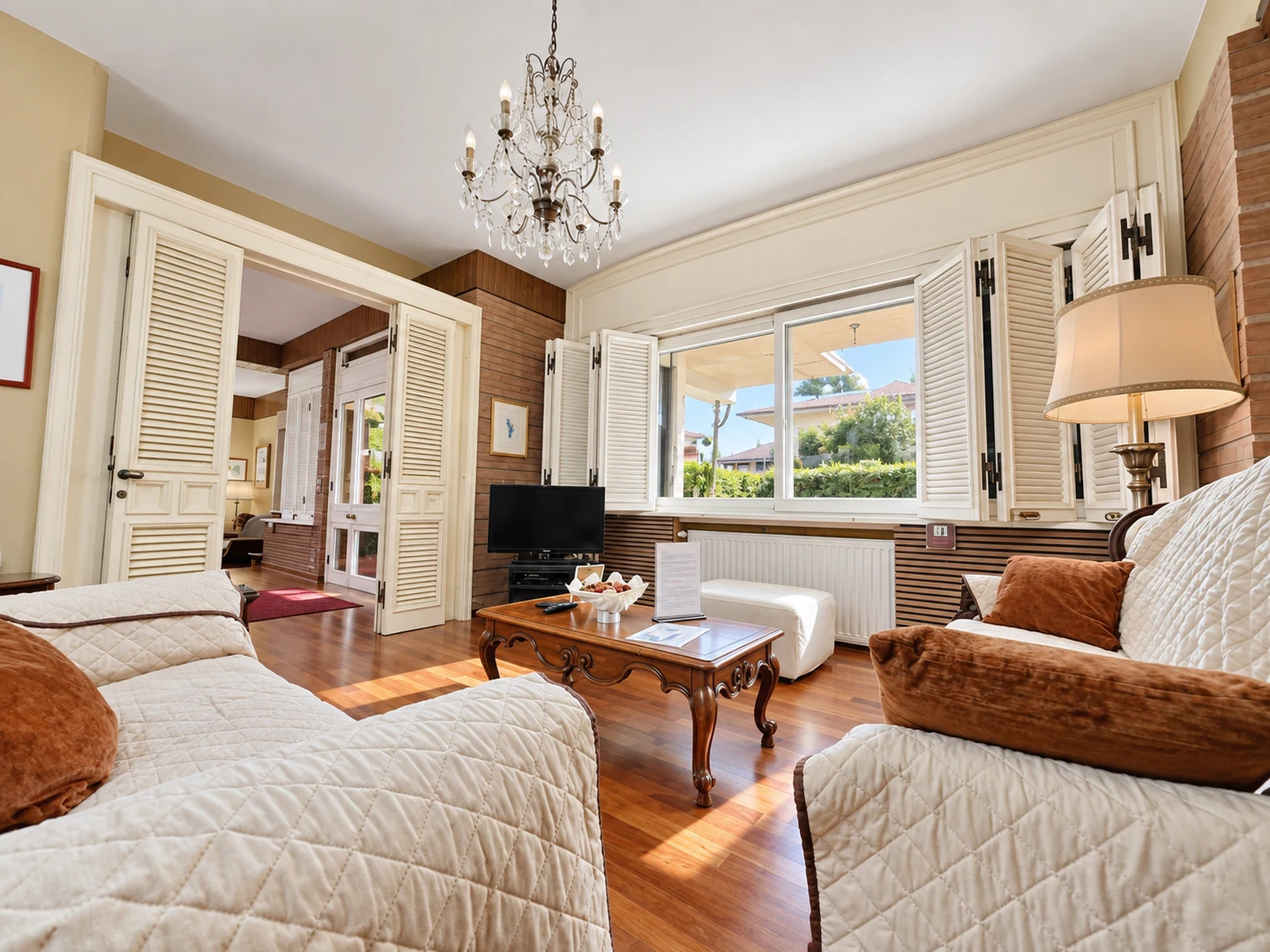 Bright living room with chandelier and louvred doors